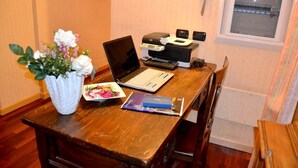 A wooden desk with a laptop, a printer, a vase with flowers, and a plate with food. - Hotel Italia 30 (Gorgonzola)