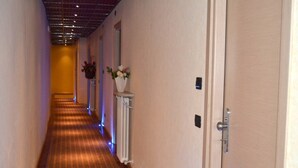 A hotel hallway with a patterned carpet, white walls, and doors on the right. - Hotel Italia 30 (Gorgonzola)