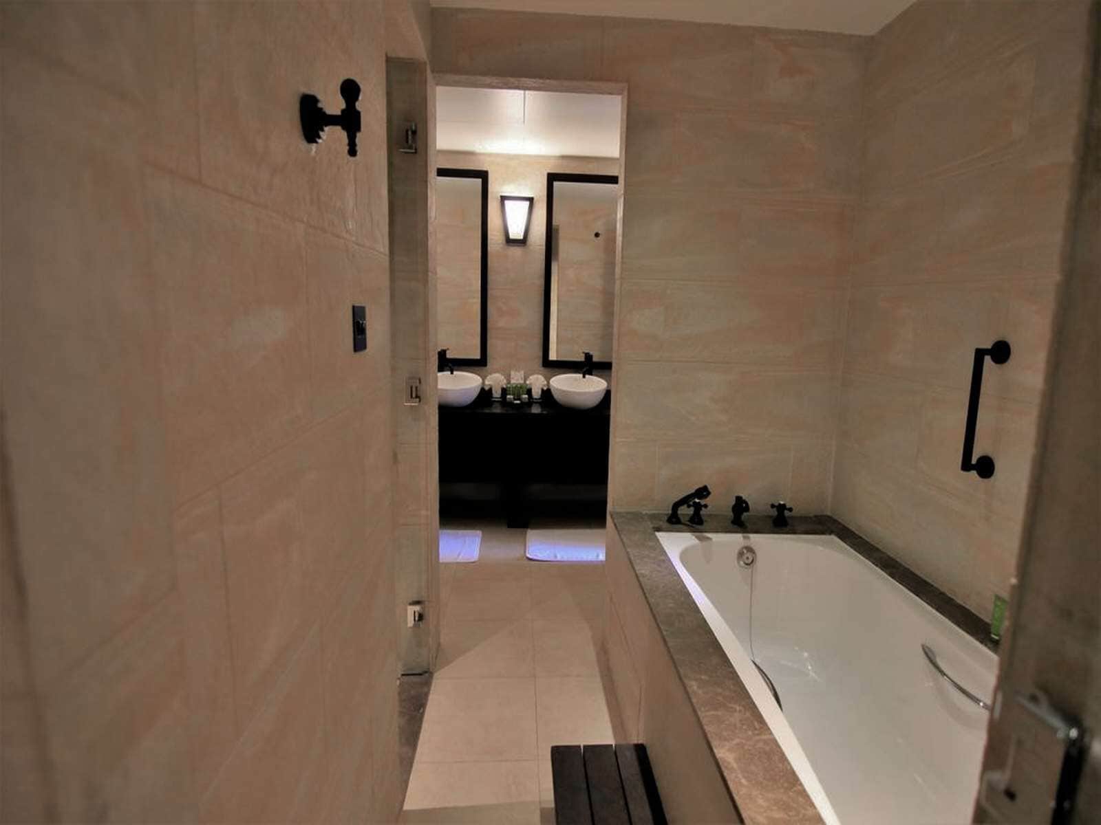 Un baño moderno con una bañera grande, una zona de lavamanos separada y un espejo.
