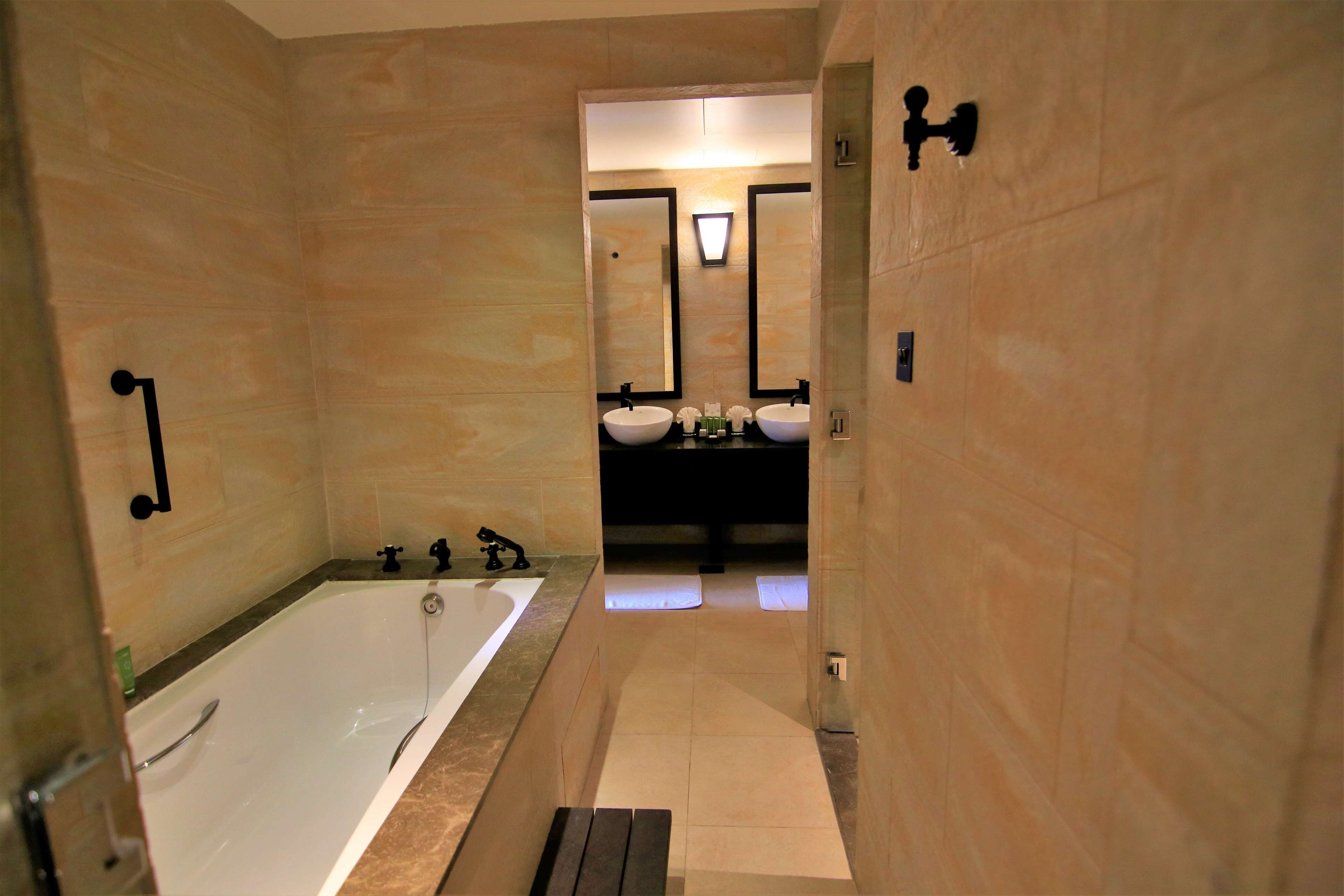 A modern bathroom with a bathtub, two sinks, and a mirror.