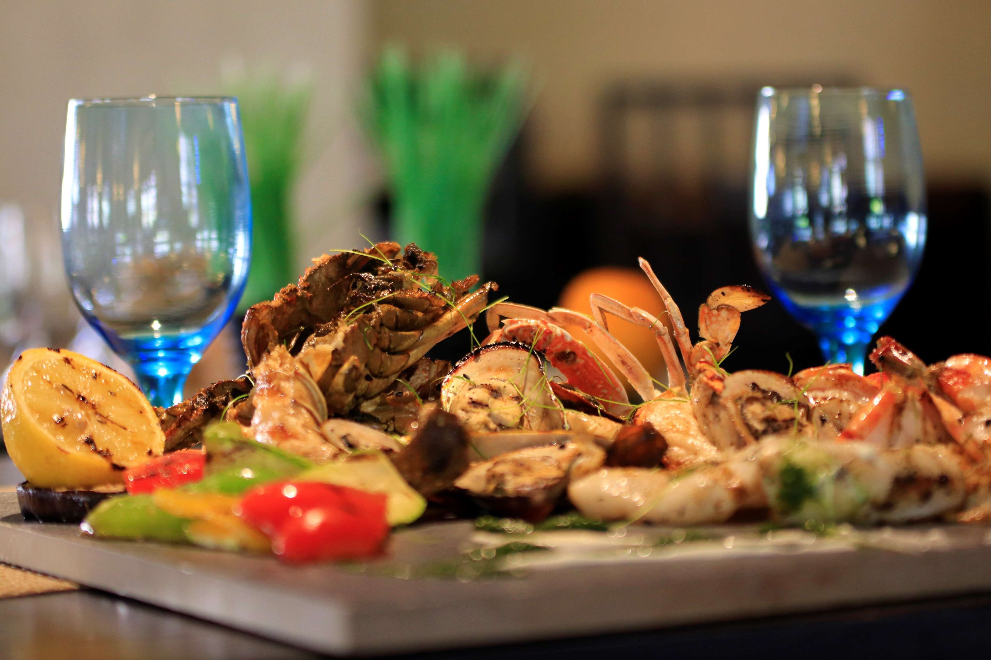 A seafood platter with grilled shrimp and vegetables, accompanied by two glasses of water.