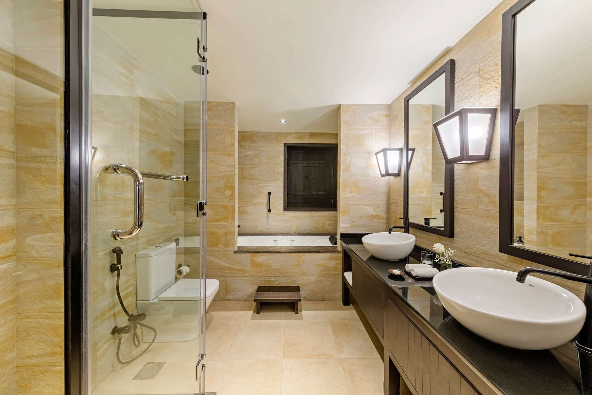 Un baño moderno con ducha acristalada, una bañera grande y dos lavamanos.