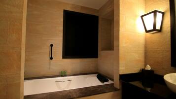 A modern bathroom with a bathtub, a wall-mounted light fixture, and a large mirror.