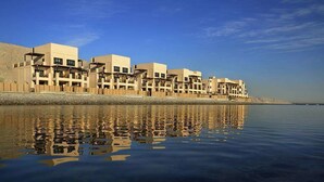 Una hilera de edificios modernos con balcones, ubicados junto a una masa de agua tranquila.