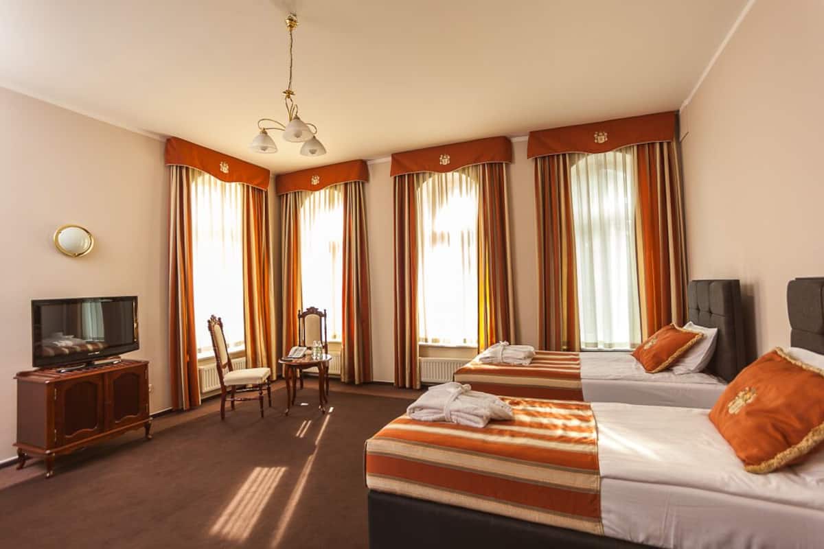 Ein Hotelzimmer mit zwei Betten, einem Fernseher, einem Schreibtisch und einem Stuhl.