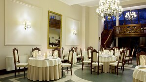Un comedor formal con varias mesas redondas, sillas elegantes y candelabros.