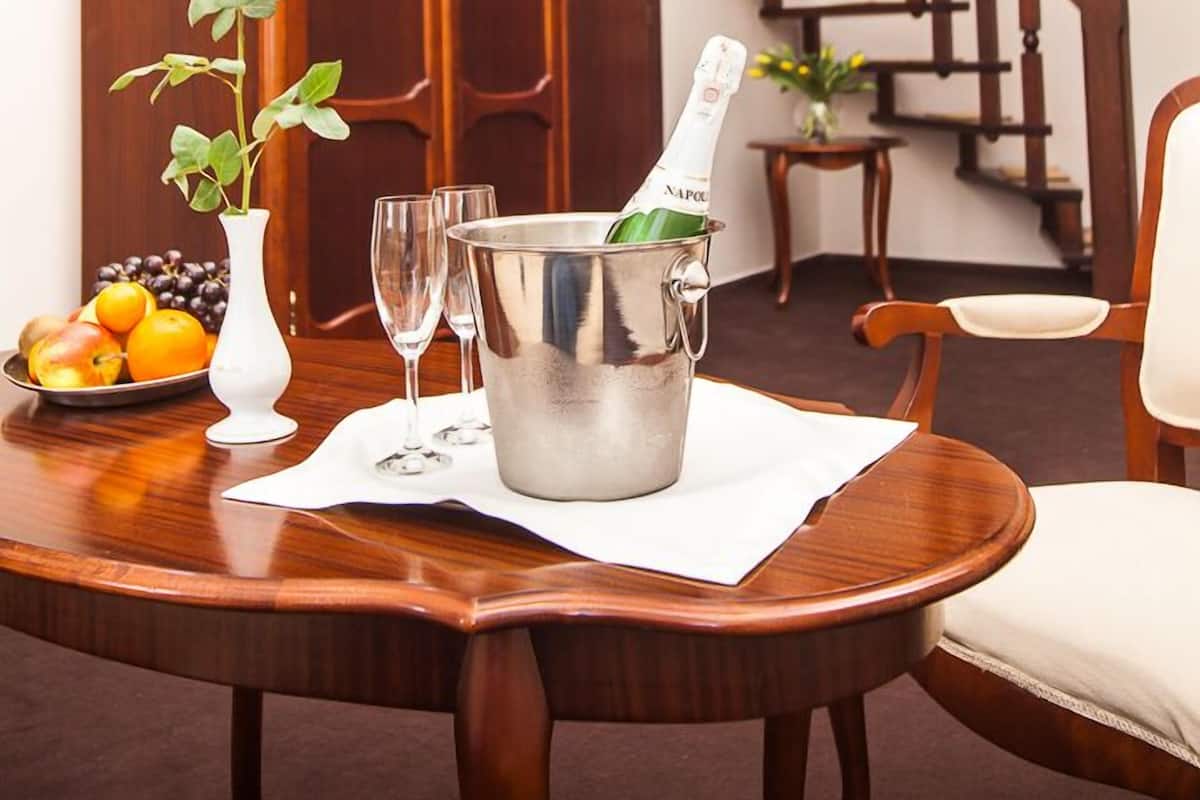 Ein Holztisch mit einer Rosenvase, einer Champagnerflasche und einer Obstschale.