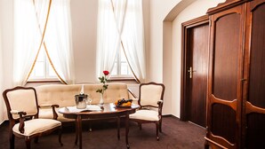 Una habitación con un sofá, dos sillones, una mesita de centro, un mueble aparador y un florero con una flor.