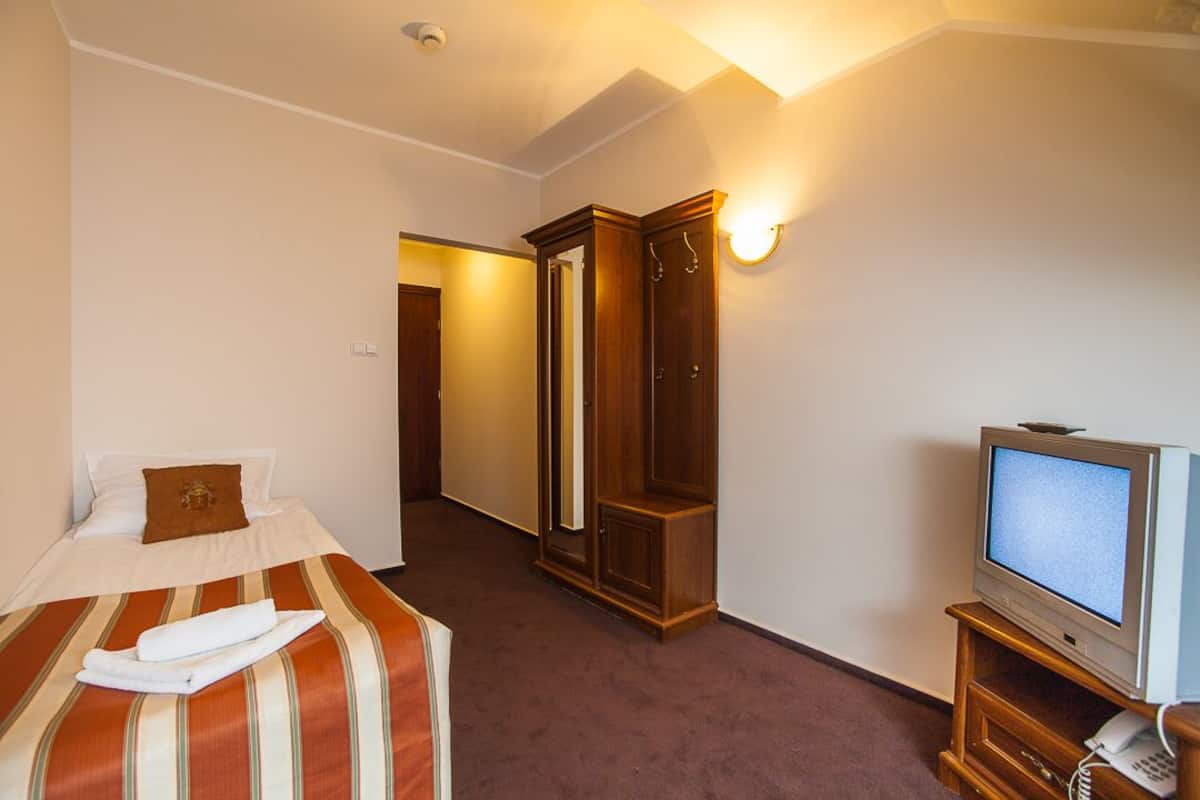 Ein Hotelzimmer mit einem Bett, einem Fernseher, einem Kleiderschrank und einem Spiegel.