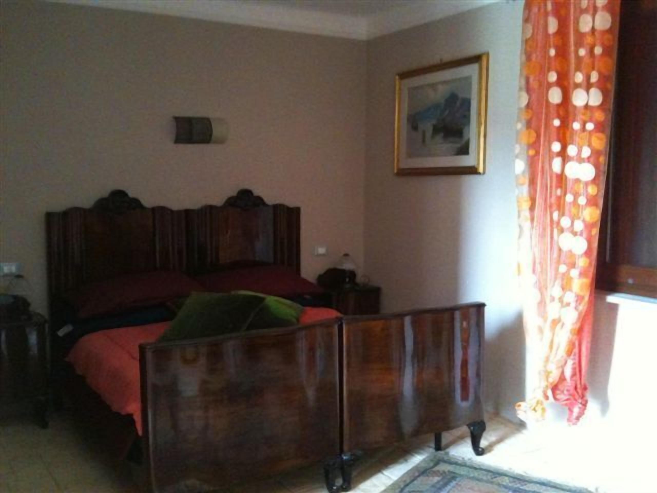 Un dormitorio con una cama de madera, una mesita de noche, una lámpara y un cuadro en la pared.