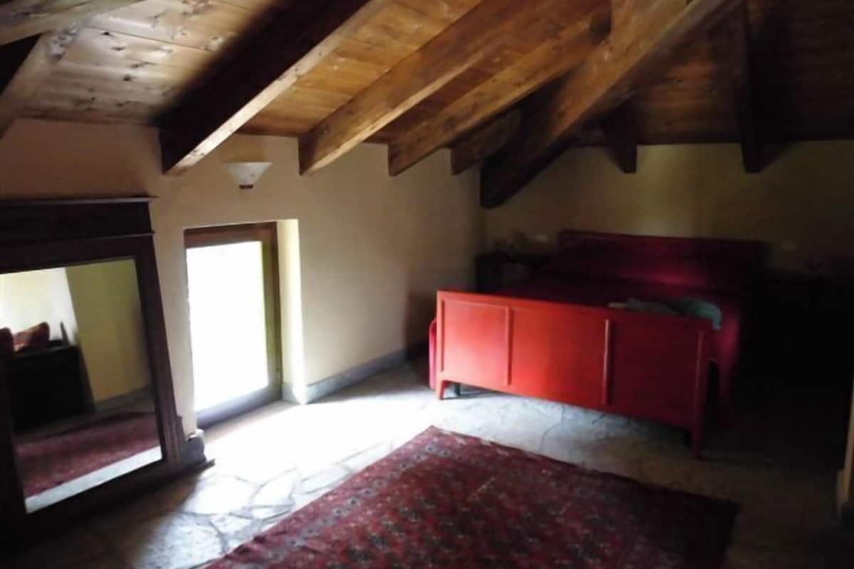A room with a sloped ceiling, a red cabinet, and a patterned rug.