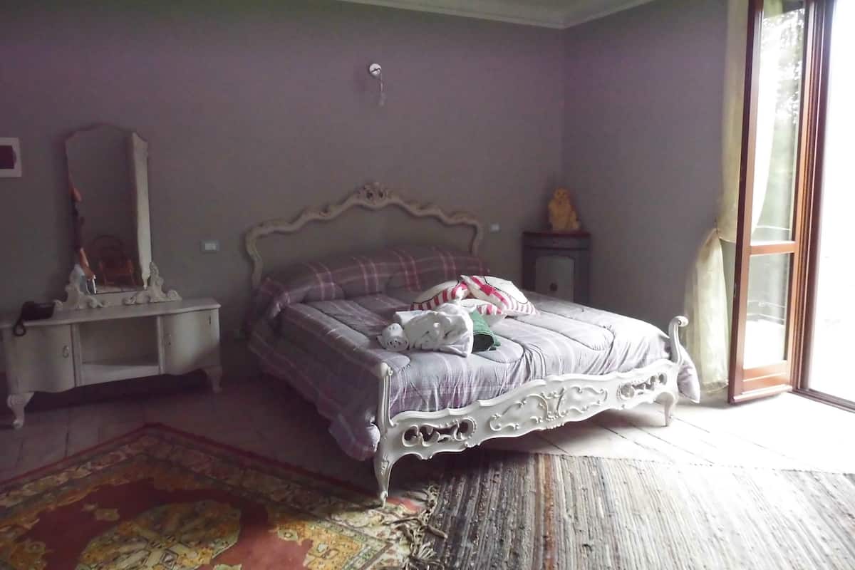 A bedroom with a bed, a dresser, a mirror, and a window.