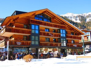 Un edificio de madera de varios pisos con balcones, un letrero de albergue de esquí y un restaurante llamado "Galzig Lodge".