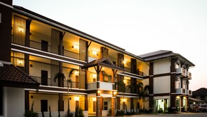 Un hotel de varios pisos con balcones, una entrada cubierta y un área de estacionamiento.