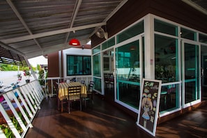 Un espace extérieur aménagé avec une table et des chaises, entouré de murs de verre et d’une terrasse en bois.