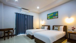 Una habitación de hotel con dos camas, un escritorio y un aire acondicionado de pared.