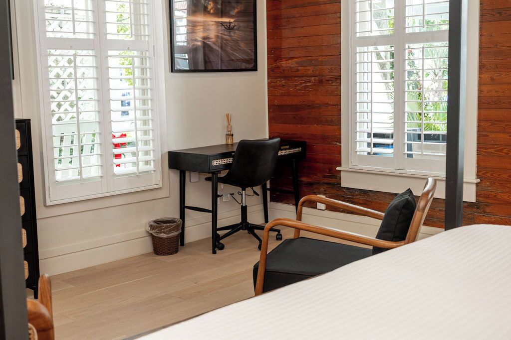 Un dormitorio con cama, escritorio y silla, y una ventana con persianas.