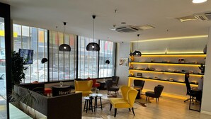 A modern interior with seating areas, a reception desk, and a wall-mounted display shelf. - Tempo Fair Suites (Istanbul)