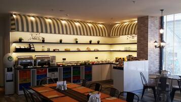 Un restaurante moderno con una mesa común alargada, una barra de café y estantes llenos de vajilla y condimentos.