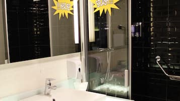 A modern bathroom with a white sink, a mirror, and a glass shower enclosure.