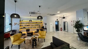 A modern lobby with a central seating area, a reception desk, and a wall-mounted shelf with decorative items. - Tempo Fair Suites (Istanbul)