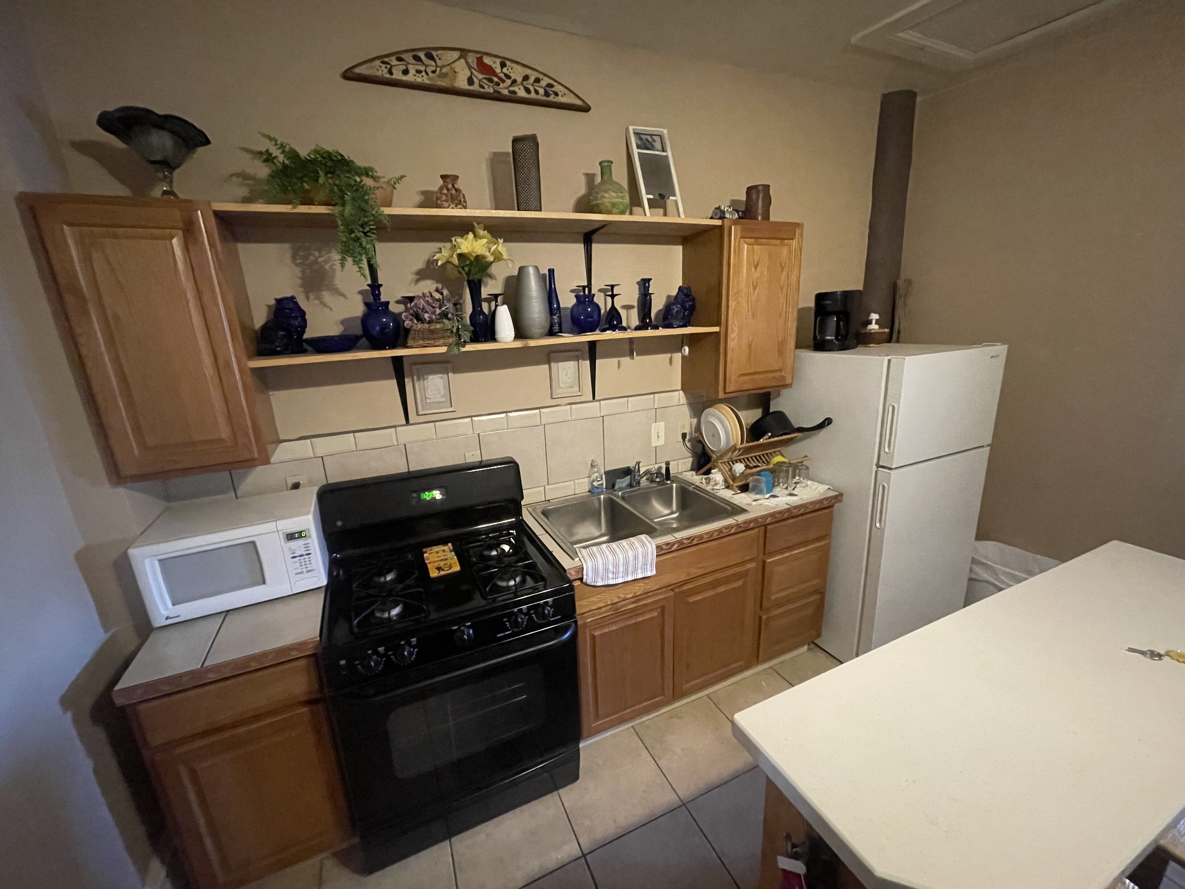 A kitchen with wooden cabinets, a stove, a microwave, and a refrigerator.
