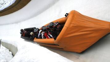Eine mit Schnee gefüllte Röhrenrutsche mit einer Gruppe von Personen in einer orangefarbenen Tube.