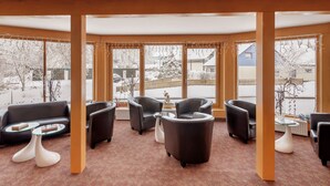 Cómoda sala de estar con sofá, sillones y una mesa de centro, con amplias ventanas que ofrecen vistas nevadas.