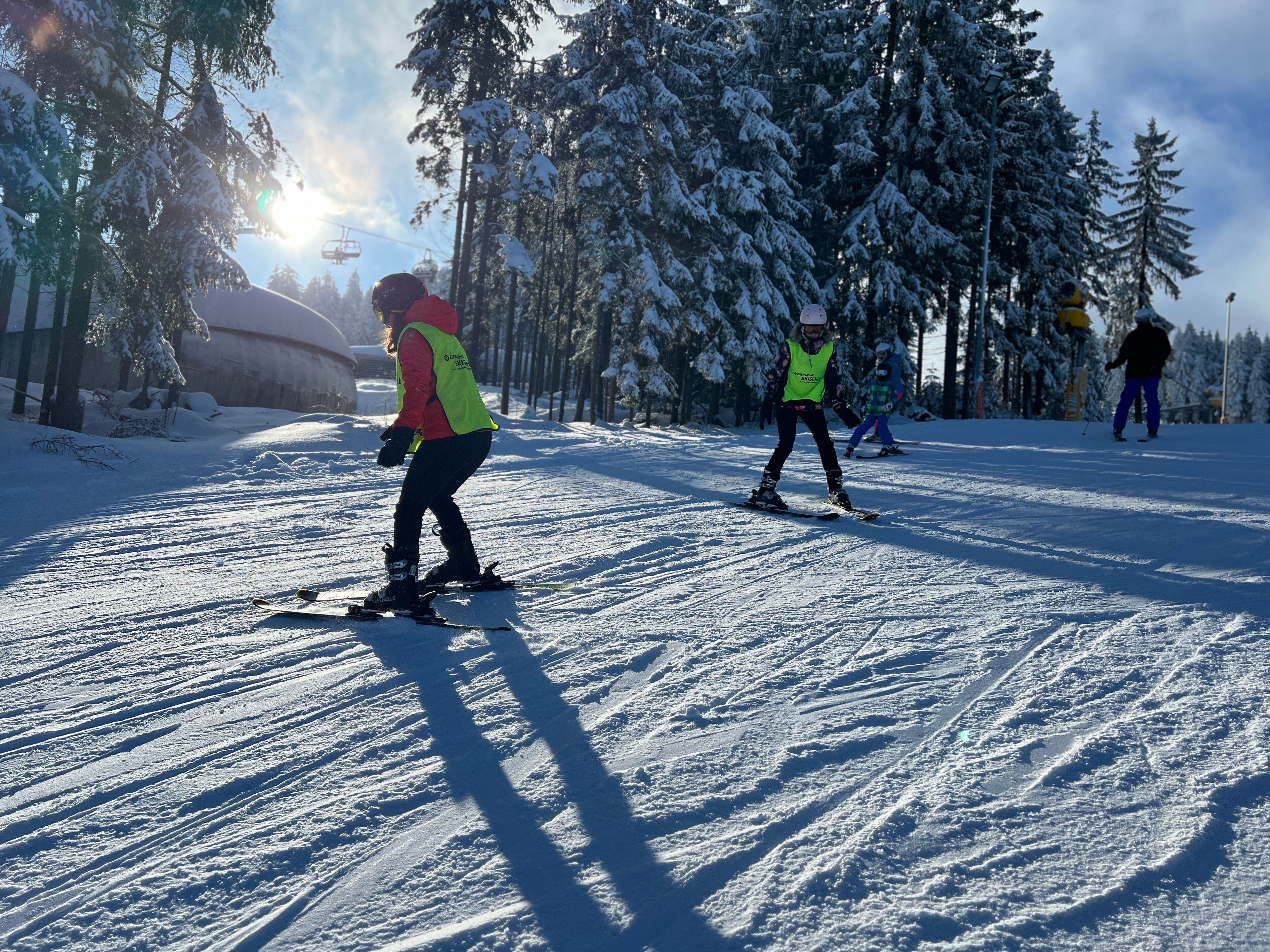 Une piste de ski enneigée, avec des skieurs et un télésiège en arrière-plan.