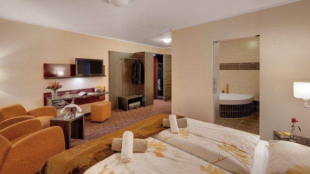 Ein Hotelzimmer mit Bett, Schreibtisch, Fernseher, Kleiderschrank und Badezimmer.