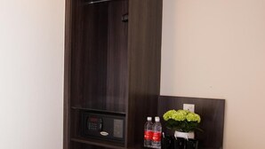 Une armoire en bois sombre, dotée d’un panneau de commande, d’une bouteille d’eau et d’un vase rempli de fleurs.