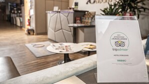A reception area with a modern design, featuring a reception desk, seating area, and a sign indicating the hotel is part of the TripAdvisor chain. - Hôtel d'Orléans (Orléans)