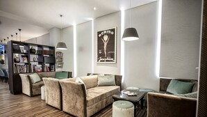 A modern living room with a beige sofa set, a coffee table, and a bookshelf filled with books and decorative items. - Hôtel d'Orléans (Orléans)