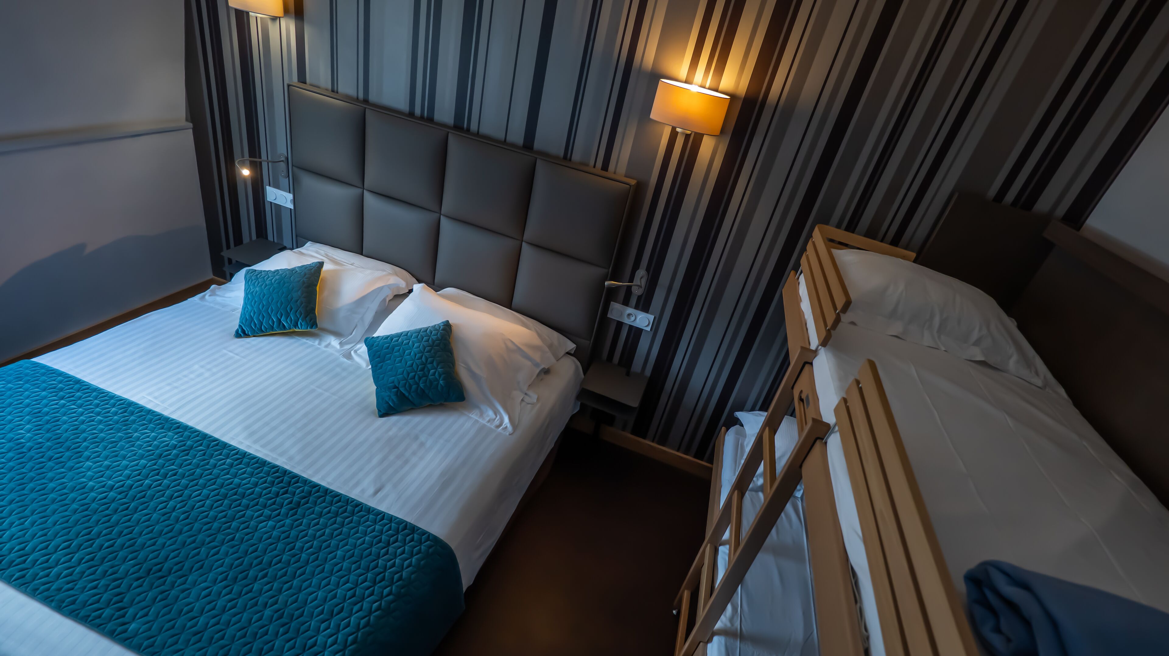 A hotel room with two beds, each with a headboard and bedside tables.