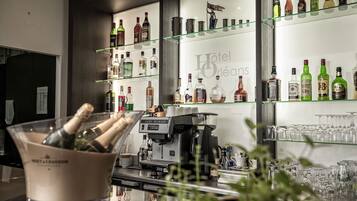 Un espace bar avec une variété de bouteilles d’alcool exposées sur des étagères, une machine à café et un seau rempli de bouteilles de champagne.