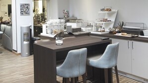 A modern kitchen with a central island, bar stools, pendant lighting, and a view into the dining area. - Hôtel d'Orléans (Orléans)