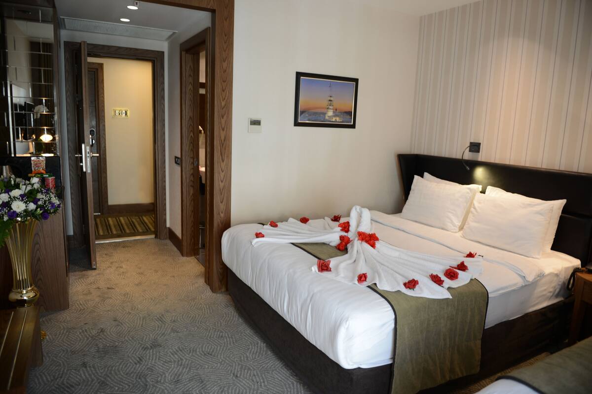 Una habitación de hotel con una cama, un cuadro en la pared y una puerta que da a otra habitación.