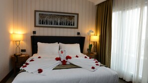 A neatly made bed with white linens and red flowers, two bedside lamps, a framed picture on the wall, and a window with curtains. - Style Hotel Sisli (Istanbul)