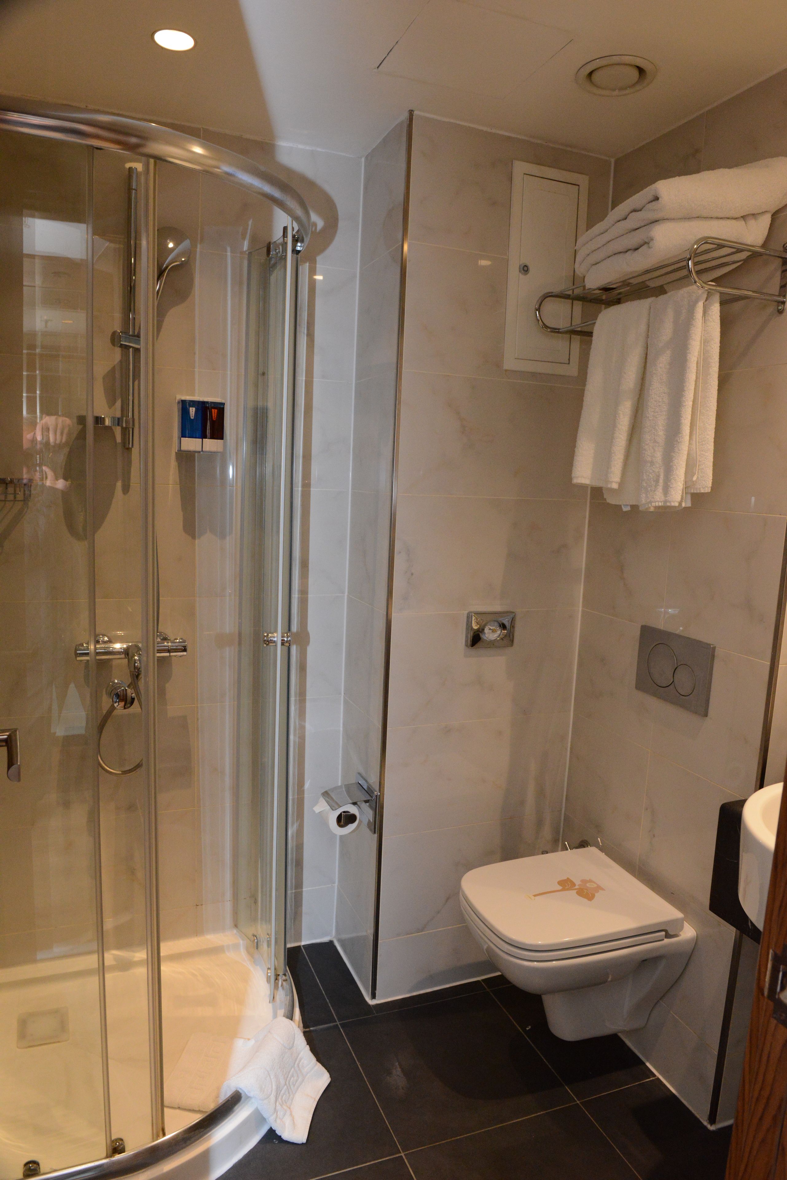 Une salle de bain avec une douche à parois de verre, des toilettes et un porte-serviettes avec des serviettes pliées.