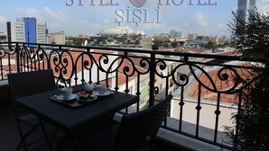 A balcony with a table set for two, overlooking a cityscape. - Style Hotel Sisli (Istanbul)