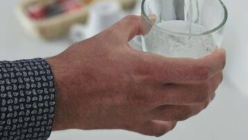 A hand holding a glass with water being poured into it.