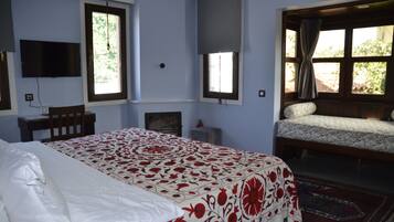 Un dormitorio con cama, escritorio, silla, televisor y ventana con cortinas.