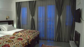 A hotel room with a bed, curtains, a television, and a rug.