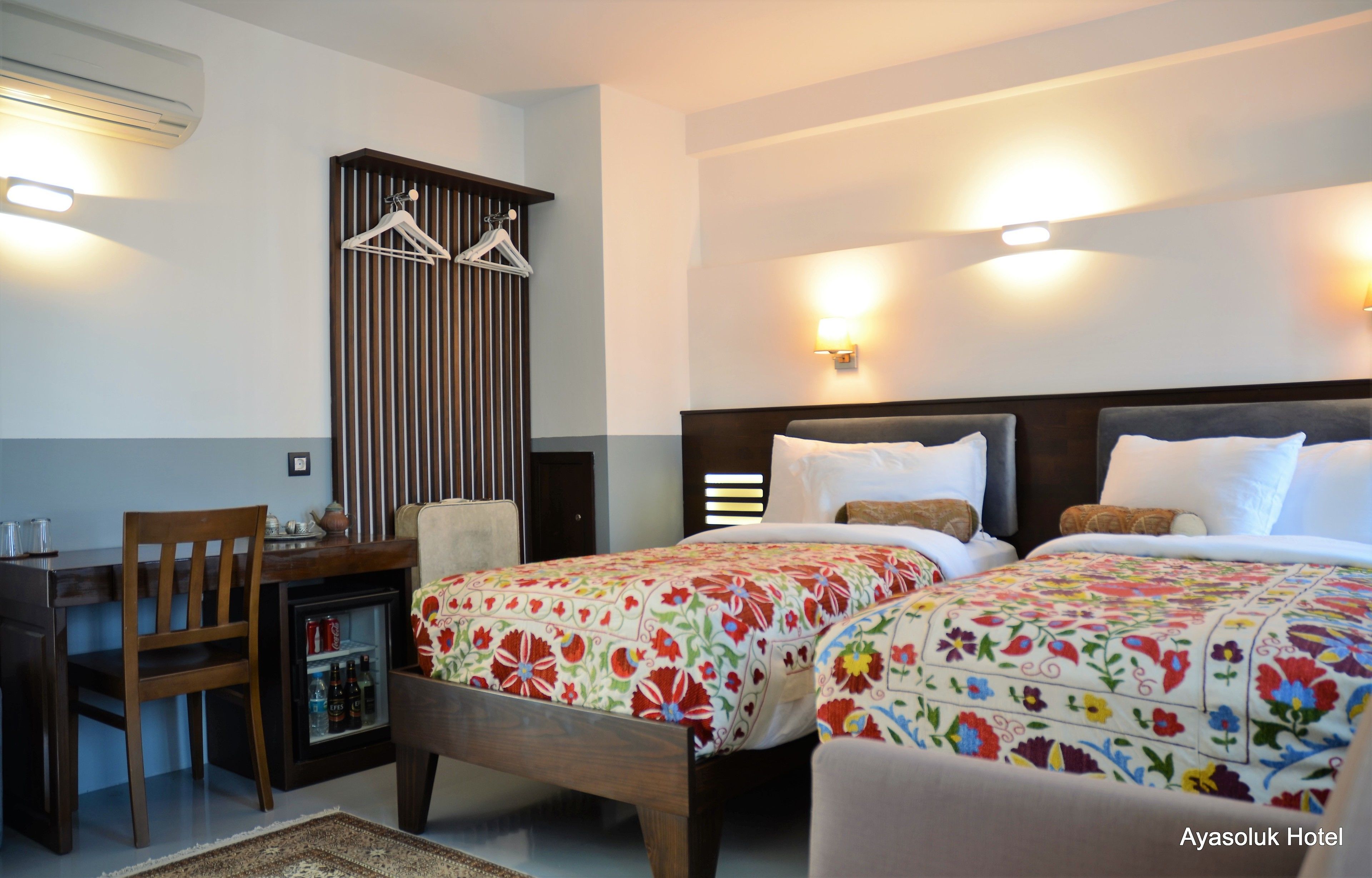 Una habitació d'hotel amb dos llits, un escriptori, una cadira i un minibar.