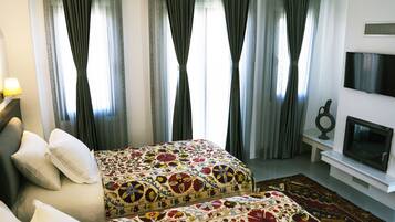 Habitación de hotel con dos camas, un televisor y un ventanal grande con cortinas.