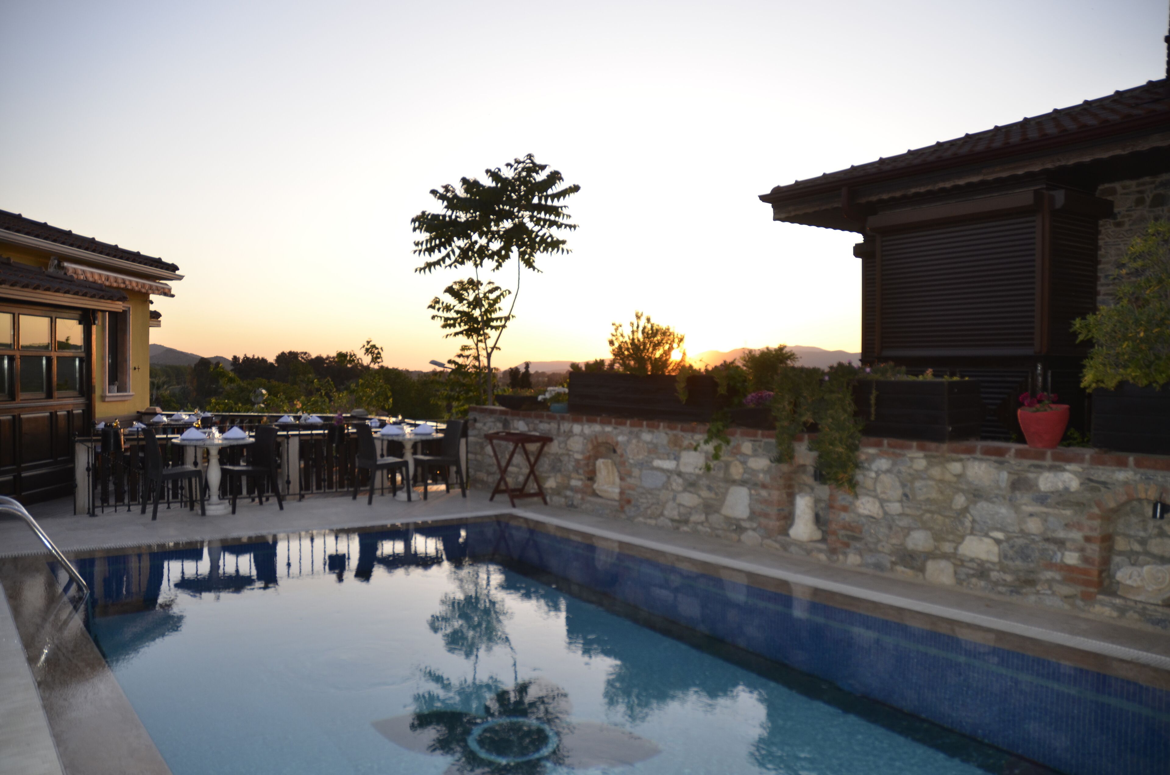 Zona de piscina con mobiliario exterior y muros de piedra.