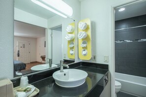A modern bathroom with a white sink, a mirror, and a towel rack. - Coastal Valley Inn (Castroville)