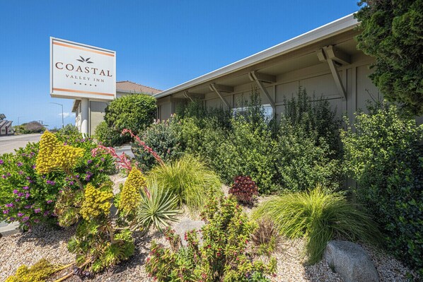 A Coastal Valley Inn sign with a garden in front. - Coastal Valley Inn (Castroville)