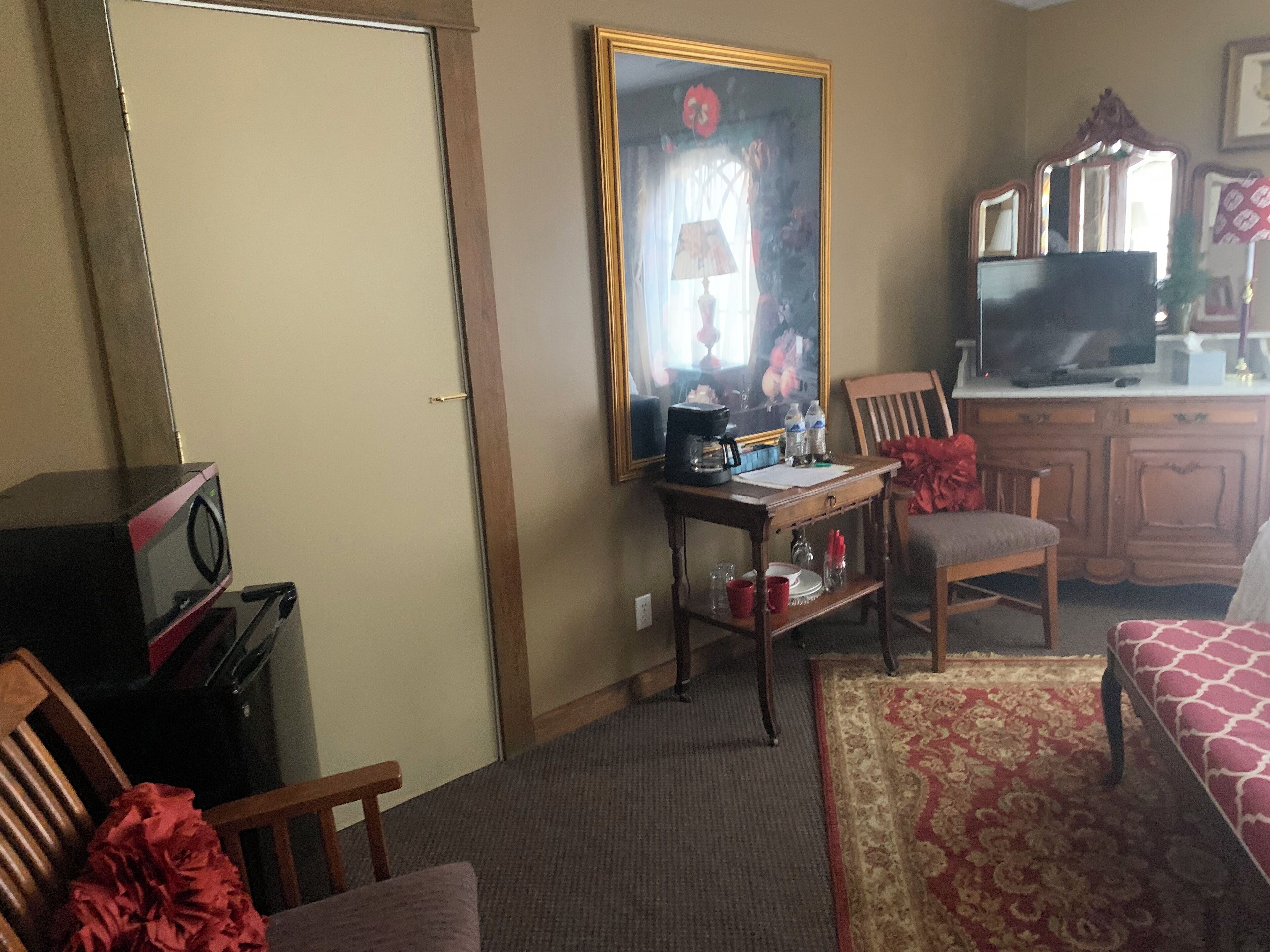 Una habitación de hotel con una cama, un escritorio con lámpara, televisión y un espejo grande.