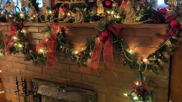 Una chimenea con un árbol de Navidad, rodeada de adornos festivos y un espejo en la parte superior.